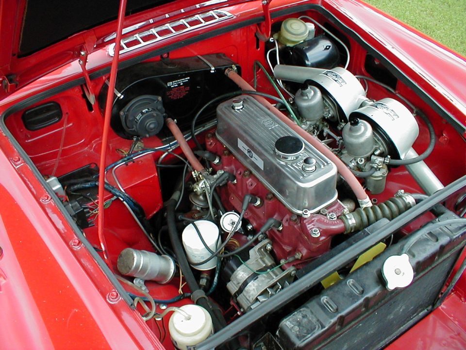 Red MGB engine bay with polished valve cover and twin SU carburetors