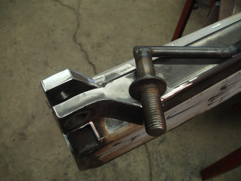 Close-up of a metal bracket with a bolt and a bent pipe welded to it, part of a custom bumper build