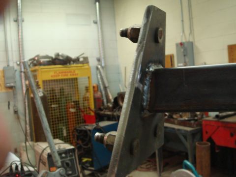 1996 Ford Bronco - A close-up view of a metal bracket and bolts, likely a custom fabrication, in a workshop environment.