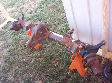 1987 Jeep Cherokee - Front axle assembly, likely from an older SUV or truck, is shown resting on orange jack stands outdoors.
