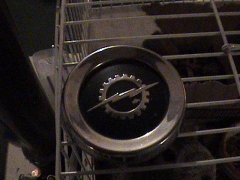 1986 Ford Bronco - Close-up of an Opel emblem, a gear and lightning bolt, mounted on a vehicle's grille.