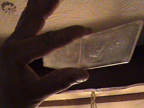 1986 Ford Bronco - A hand holds a clear plastic component, its contents obscured by shadow and debris.