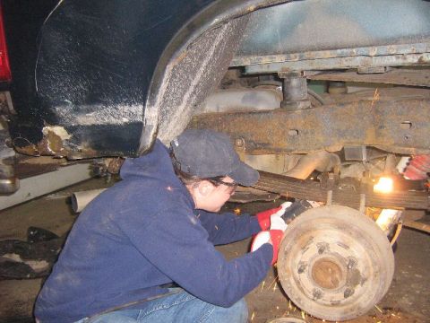 1995 Ford Bronco - A person is working on the rear suspension of a vehicle, possibly making repairs or modifications.