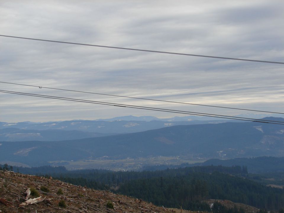 Overcast sky above distant blue mountains and a deforested hillside