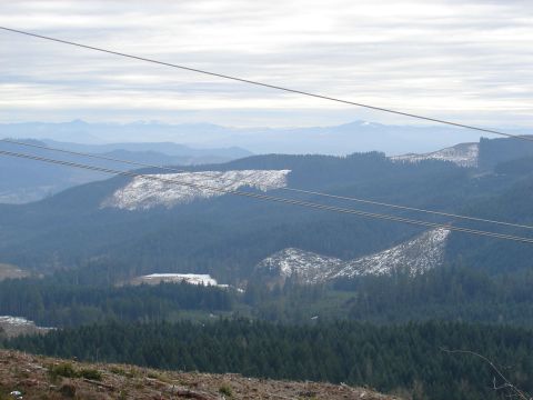 1996 Ford Bronco - Power lines traverse a wide mountain vista with snow-dusted hills and dense evergreen forests.