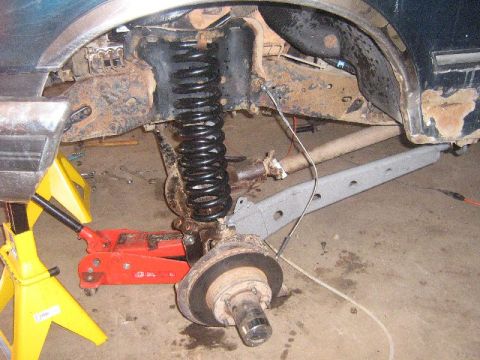 1995 Ford Bronco - Undercarriage of a vehicle undergoing repair, showing suspension components and a wheel hub.