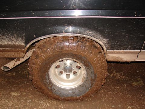 1996 Ford Bronco - Mud covers the tire and fender of a vehicle, showing off-road use.