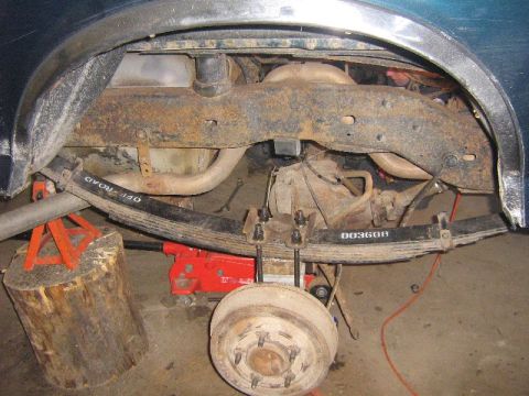 1995 Ford Bronco - Close-up view of the rear suspension and axle assembly of a vehicle, showing leaf springs and brake drum.
