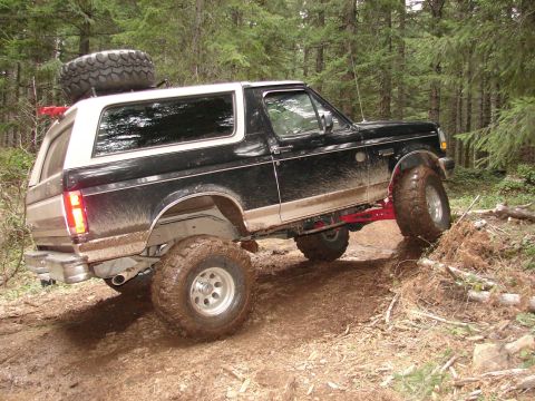 1996 Ford Bronco - This 1996 Ford Bronco navigates a challenging muddy path through a wooded area.