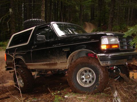 1996 Ford Bronco - This lifted 1996 Ford Bronco tackles a challenging, muddy path through a dense forest.
