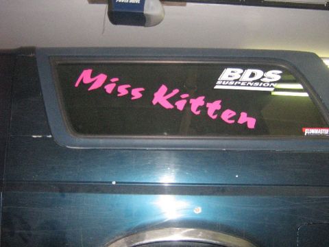 1995 Ford Bronco - A dark blue SUV is shown with custom decals on its rear window, including 'Miss Kitten' and brand names.