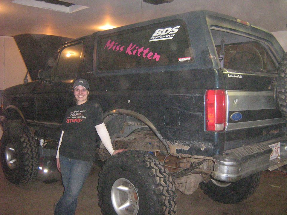 Dark green Ford Bronco with lifted suspension and large tires, a woman stands beside it