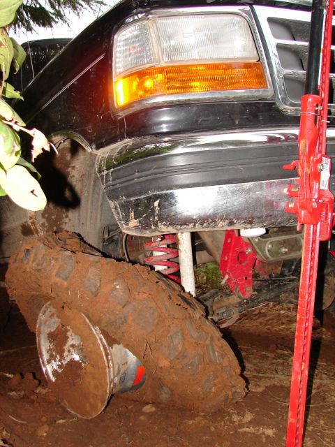 1996 Ford Bronco - A Ford F-Series truck is stuck in the mud, with a jack positioned to lift it out.