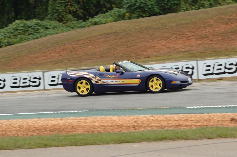 Dark blue Corvette convertible Indy 500 pace car with yellow wheels on a racetrack, side view