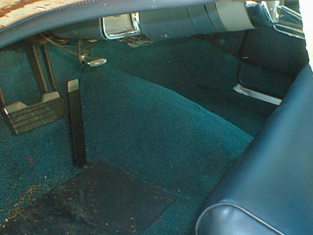 Teal carpet and pedals in driver footwell of a car with blue vinyl seats