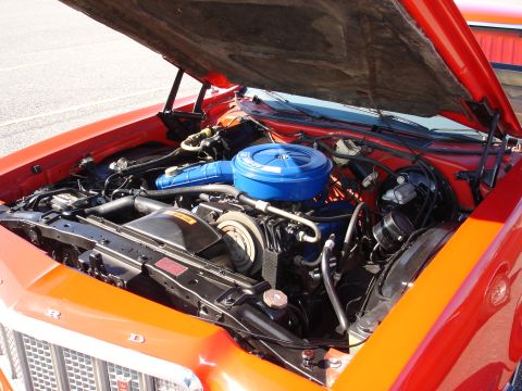 1979 Ford Ranchero - The engine bay of an orange 1979 Ford Ranchero is open for inspection.