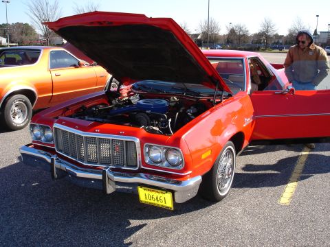 1979 Ford Ranchero - Two Ford Rancheros are parked side-by-side, one red with its hood up, the other orange.