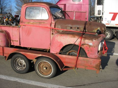 1952 Ford Pickup - A weathered red pickup truck, likely from the late 1940s, is secured to a trailer.