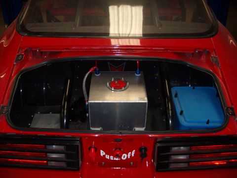 1984 Ford Bronco - The rear cargo area of a red car contains a fuel cell and a blue cooler.