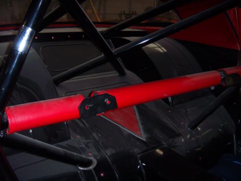 1984 Ford Bronco - The interior of a race car is visible, a prominent red bar and black roll cage structure.