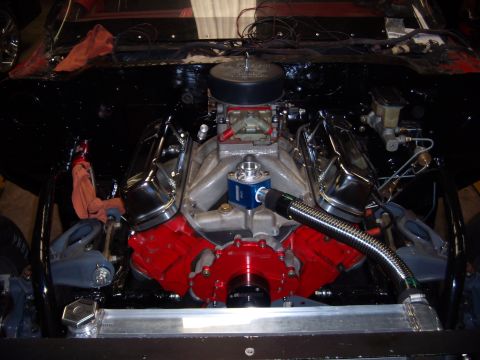 1984 Ford Bronco - Engine bay view of a V8 engine chrome valve covers and a red engine block, likely undergoing restoration or modification.