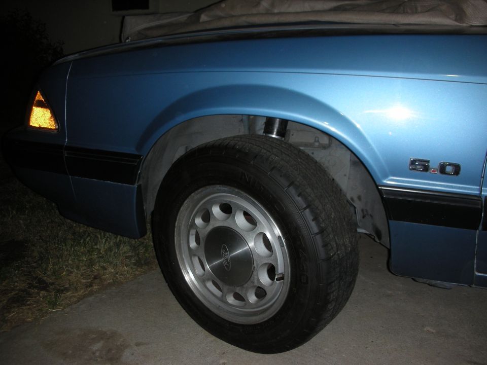 Blue 1990 Ford Mustang side view showing fender, wheel, and "5.0" badge