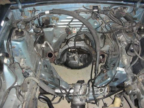 1990 Ford Mustang - This photo shows the engine bay of a car with the transmission removed, revealing the underlying mechanical components.