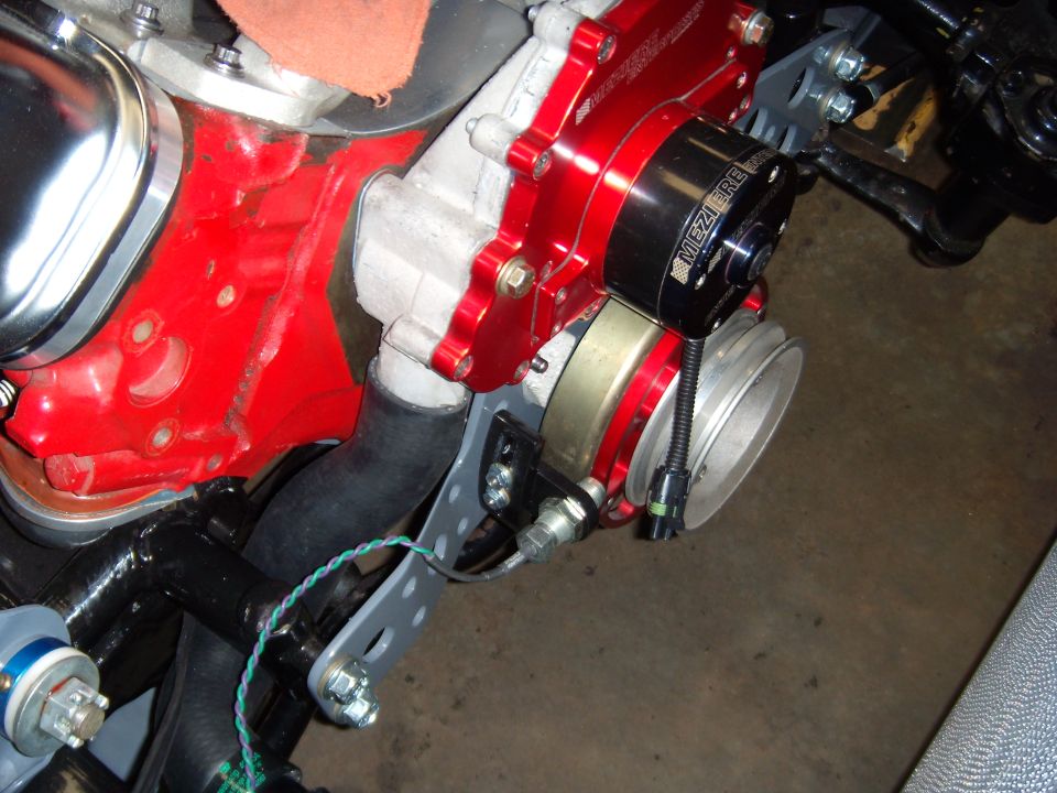 Close-up of an aftermarket red aluminum water pump and pulley assembly on an engine block