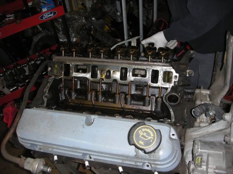 1990 Ford Mustang - Close-up of a disassembled Ford V8 engine, with a person's hands visible working on it.