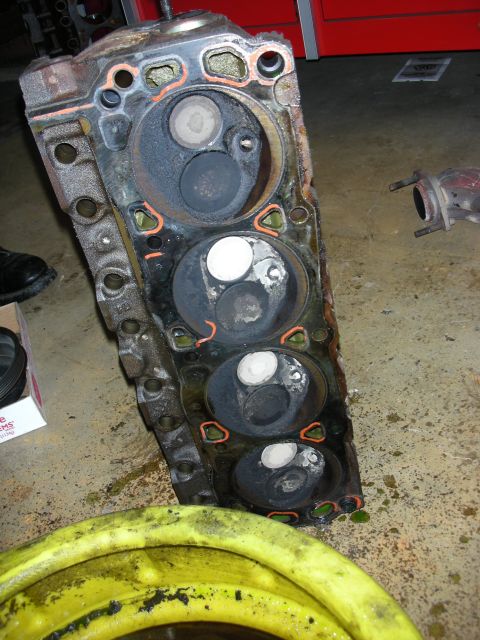 1990 Ford Mustang - A used engine cylinder head sits on a garage floor, showing signs of wear and tear.