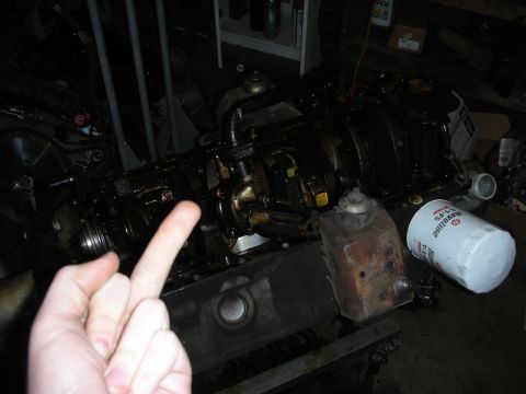 1990 Ford Mustang - A hand is shown in the foreground, obscuring part of an engine block and an oil filter.
