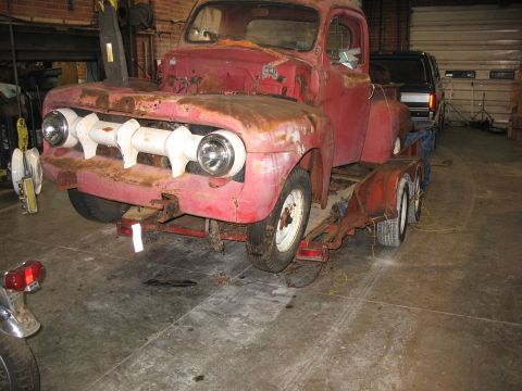 1952 Ford Pickup - Front view of a rusty red 1952 Ford Pickup truck being transported on a trailer.