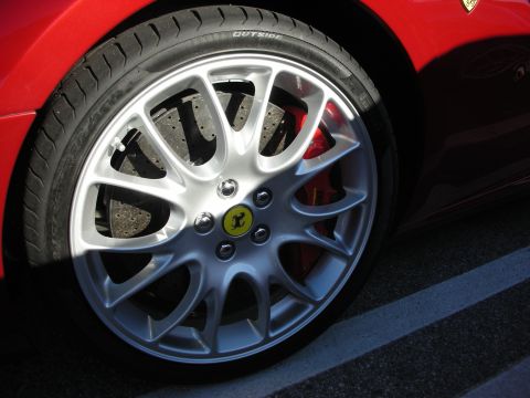 1998 Ford Crown Victoria - Detail of a Ferrari's silver multi-spoke alloy wheel, prancing-horse center cap and red brake caliper on a red car.