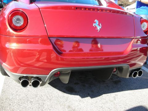 1998 Ford Crown Victoria - rear bumper of a red Ferrari, showing prancing-horse badge, twin pairs of round exhaust tips and a gray diffuser.