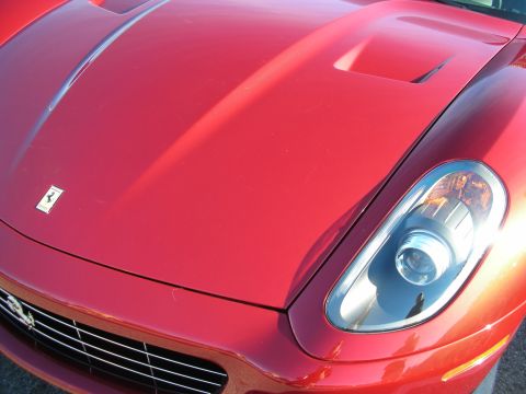 1998 Ford Crown Victoria - Detail of a red Ferrari's hood, fender badge and round headlight with a vented hood scoop.
