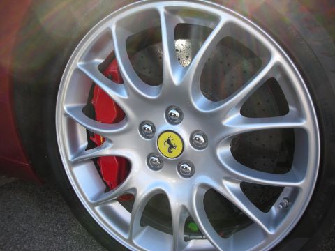 1998 Ford Crown Victoria - Detail of a Ferrari's silver multi-spoke wheel, prancing-horse center cap and red brake caliper on a dark red car.