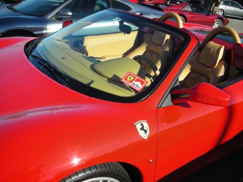 1998 Ford Crown Victoria - red Ferrari spider with tan leather interior and prancing-horse fender badge sits in a crowded parking lot.