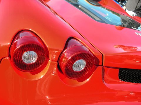 1998 Ford Crown Victoria - Detail of a red Ferrari's two round red taillights and rear quarter with a black mesh vent.