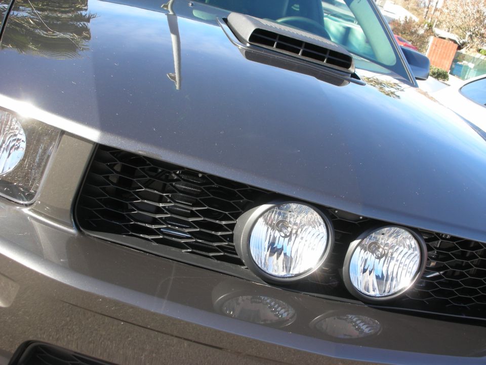 Front grille close-up of a gray Mustang with round driving lights