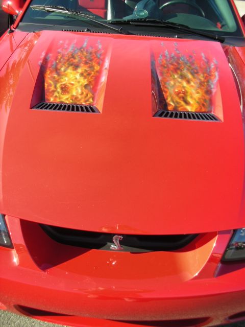 1998 Ford Crown Victoria - red Ford Mustang's hood with twin scoops displaying airbrushed flame graphics and a Cobra snake badge.