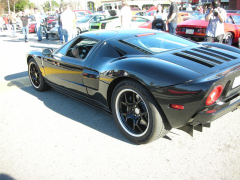 1998 Ford Crown Victoria - black Ford GT mid-engine supercar shown in rear three-quarter view with black wheels, parked among other show cars.