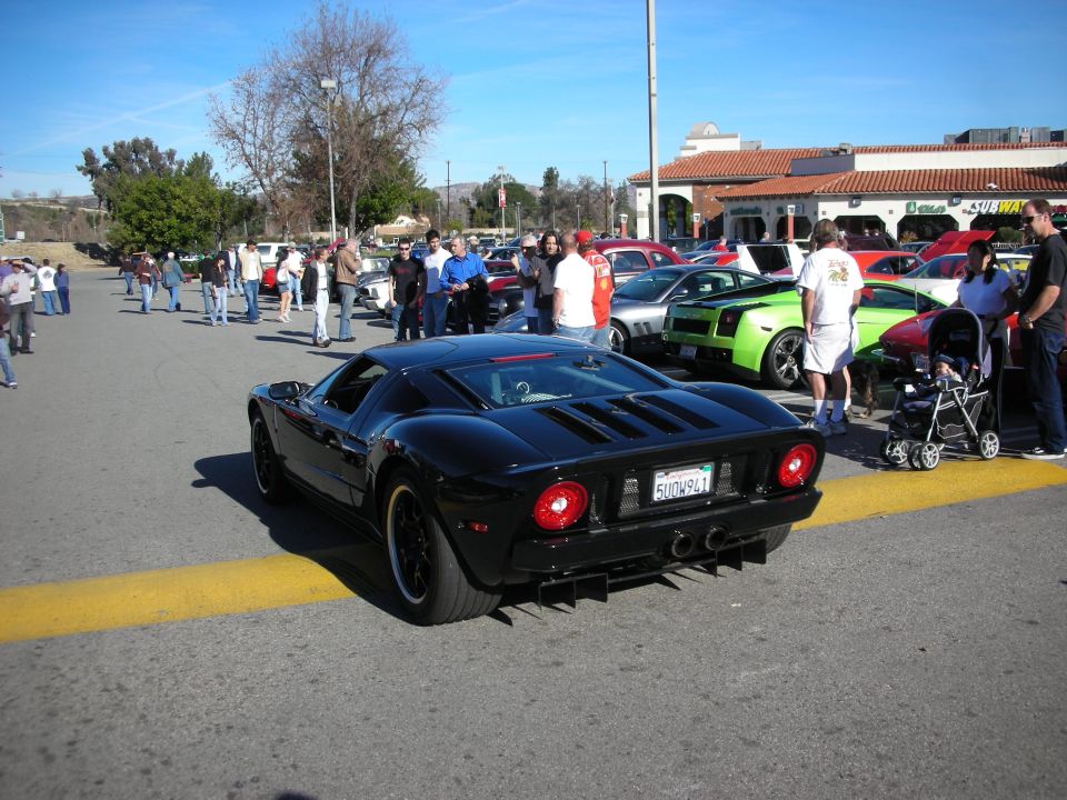 Black Ford GT rear view with round taillights at busy car-show lot