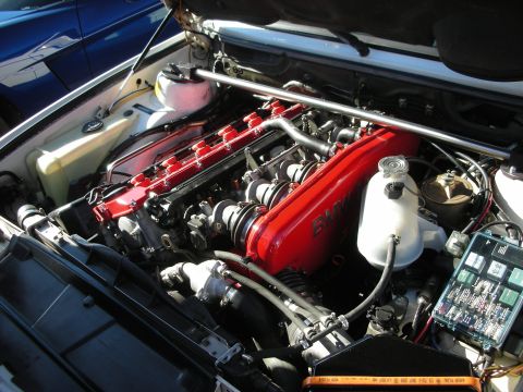1998 Ford Crown Victoria - red-painted BMW inline-six engine with strut brace and fuse box, neatly detailed in a clean engine compartment.