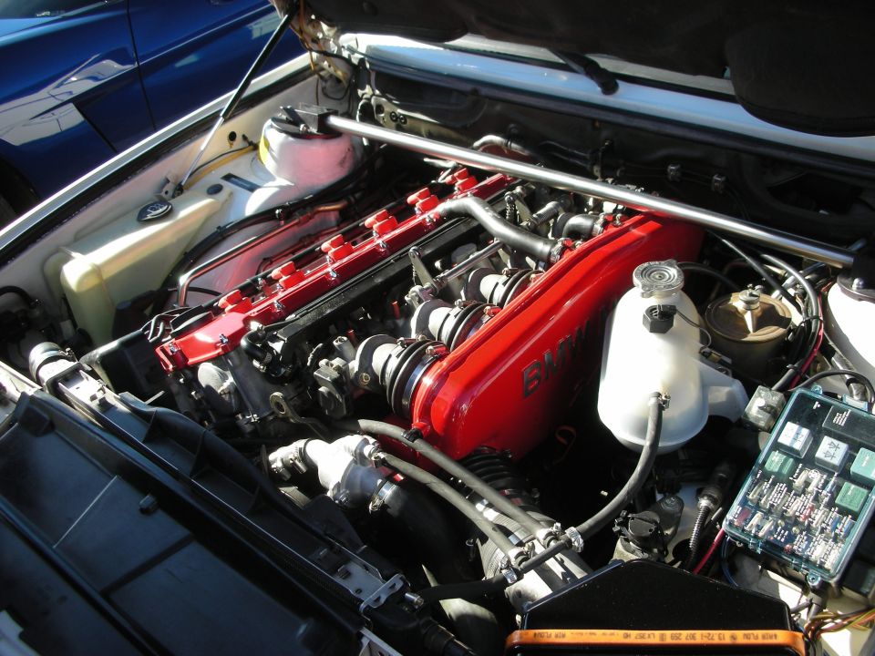 Red inline-six engine with BMW valve cover in a clean engine bay