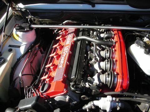 1998 Ford Crown Victoria - red BMW M Power inline-six engine sits in a tidy engine bay with strut brace and reservoir tanks visible.