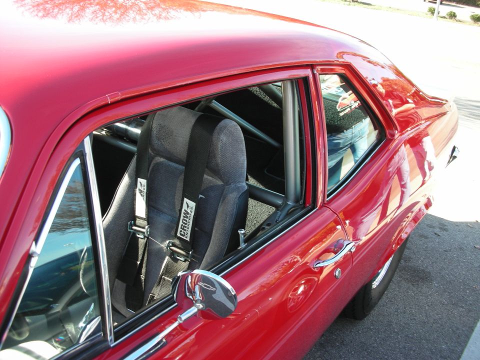 Interior of red muscle car through window showing roll cage and racing seat