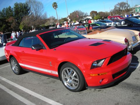 1998 Ford Crown Victoria - red Ford Shelby GT500 convertible with white stripes and chrome wheels parked among other cars at a meet.