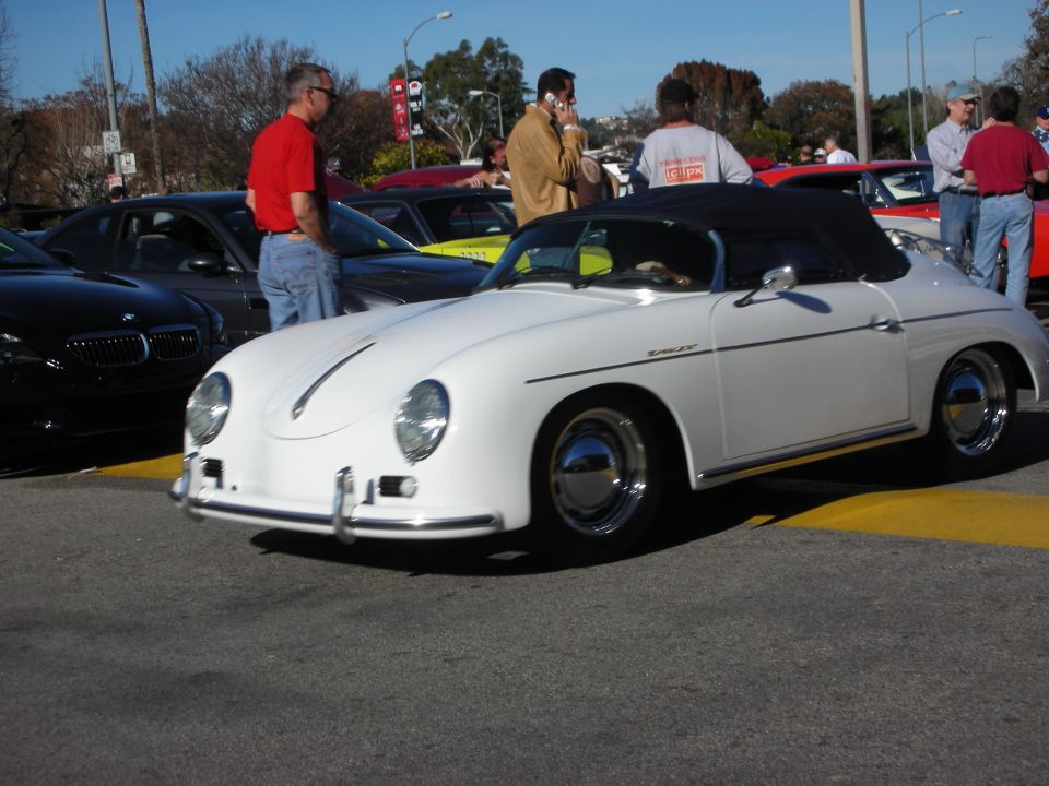 White Porsche 356-style speedster convertible at a busy outdoor car meet