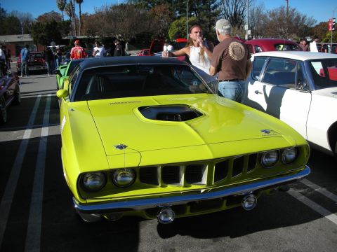 1998 Ford Crown Victoria - lime-green Plymouth Barracuda muscle car with hood scoop and quad headlights parked at a crowded outdoor meet.