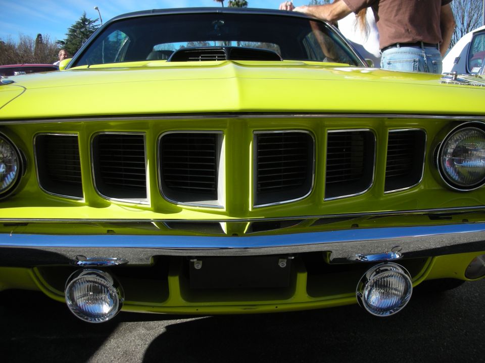 Front grille close-up of a lime-green Plymouth Cuda with dual fog lamps
